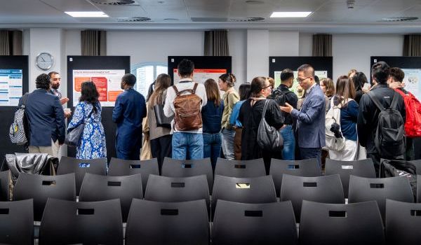 Conference attendees stood talking to each other in front of display of research posters