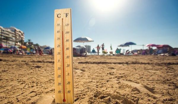Thermometer showing a high temperature stuck in the sand on a beach