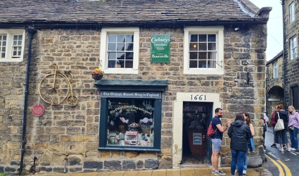 Group of PGRs outside a shop with a sign reading "The oldest sweet shop in England"