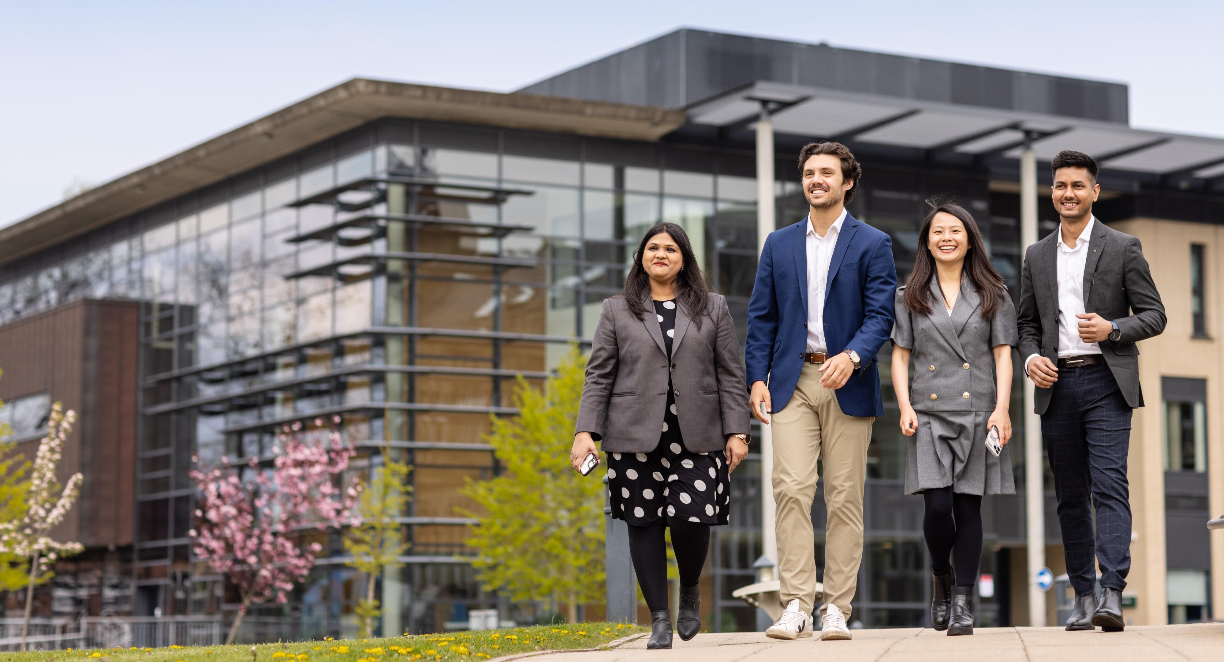 Four students walking in front of a modern building