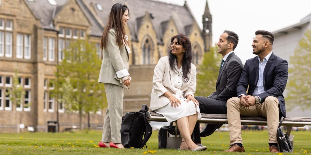 Four MBA students sitting outside the Maurice Keyworth building.