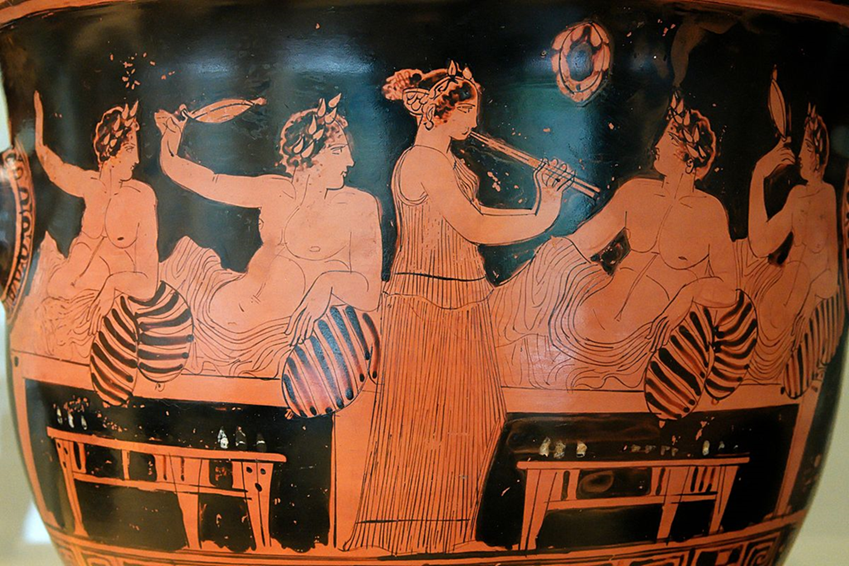 Greek vase: depicts men feasting and a women playing the flute to entertain them