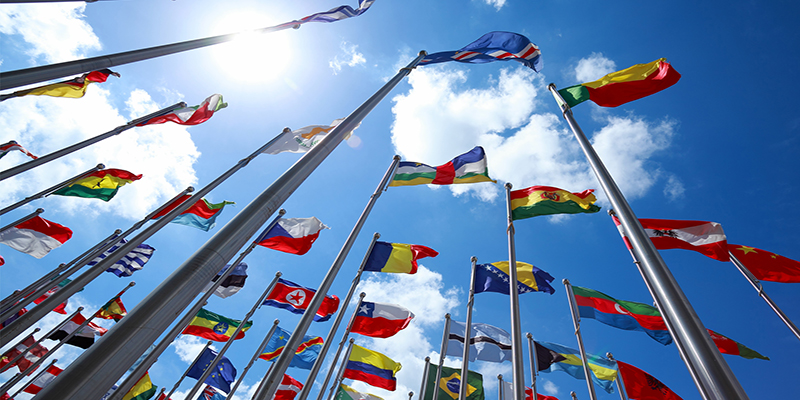 Upwards shot of flags of the world in front of blue sky