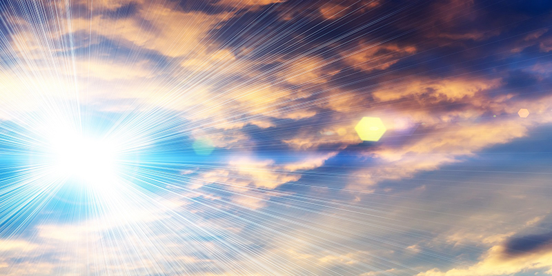 A colourful shot of a blue sky with fluffy clouds and bright sunshine