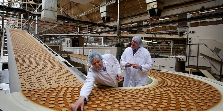 Officials standing besides a factory production line