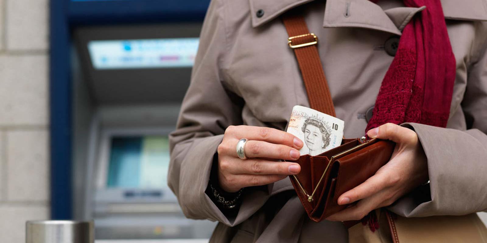 Woman placing cash into her purse after withdrawing it from an ATM