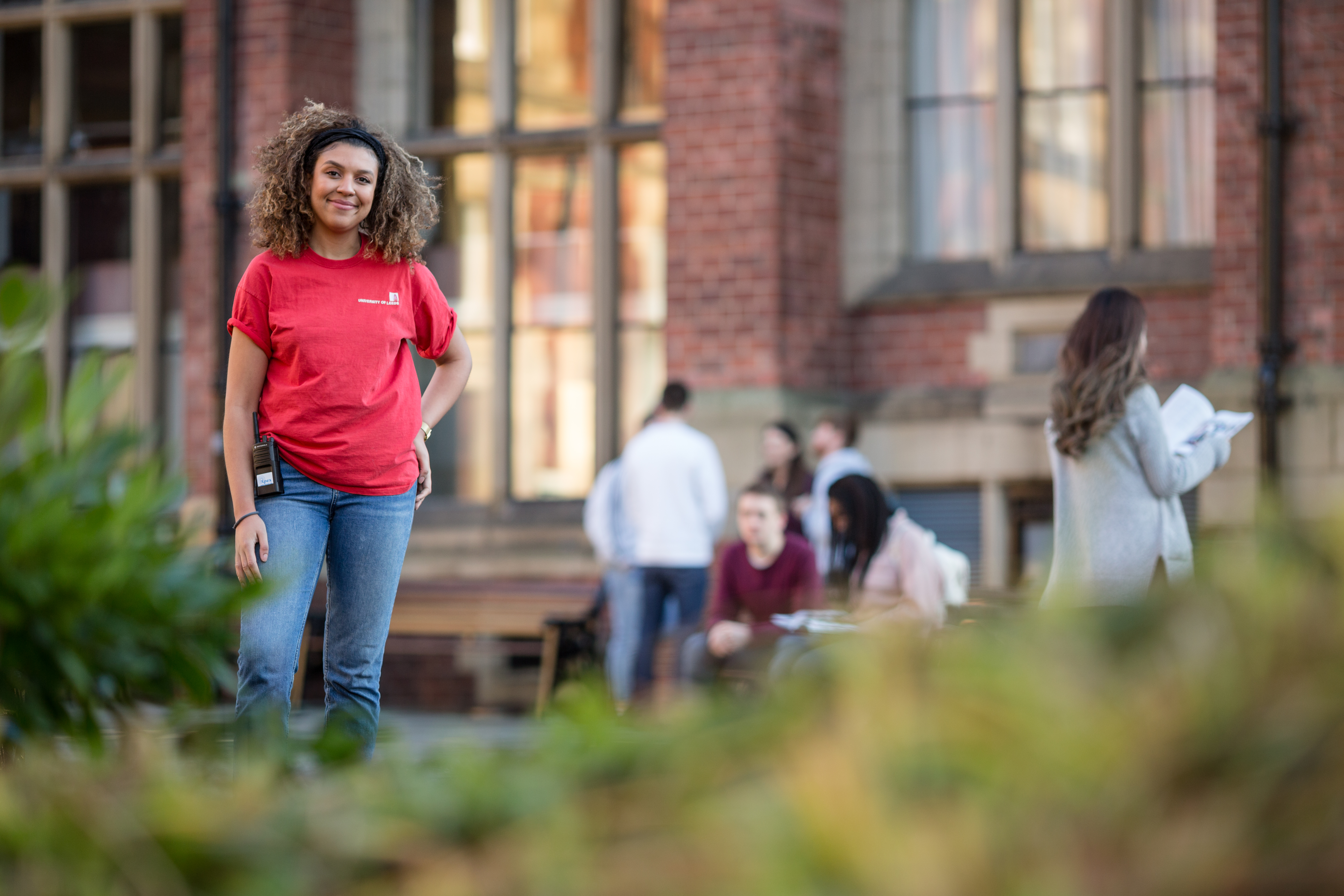 Student stood outside the Great Hall on campus wearing a red ambassador t-shirt