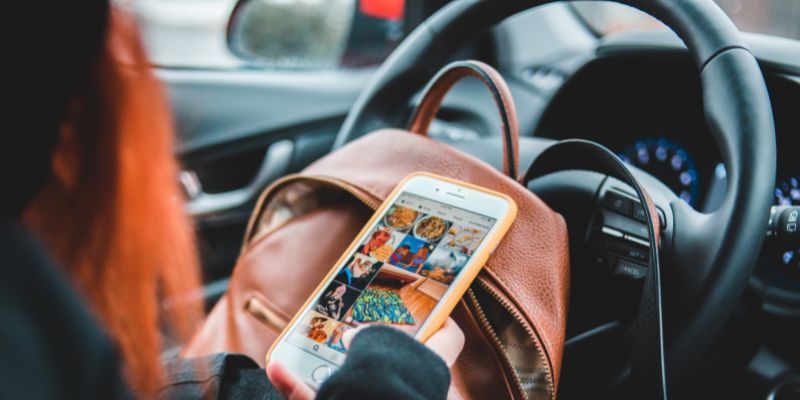 Person scrolling through photos on a phone whilst sat in a car