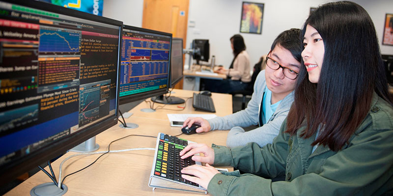 2 students in the trading room working at a computer