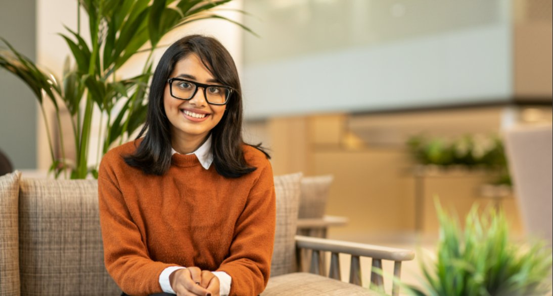 Student sitting on a cafe seat, looking straight to camera