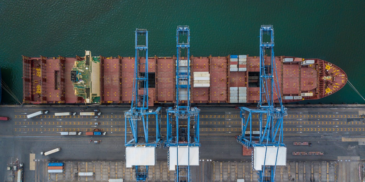 Shipping containers on docked ship with cranes arial view