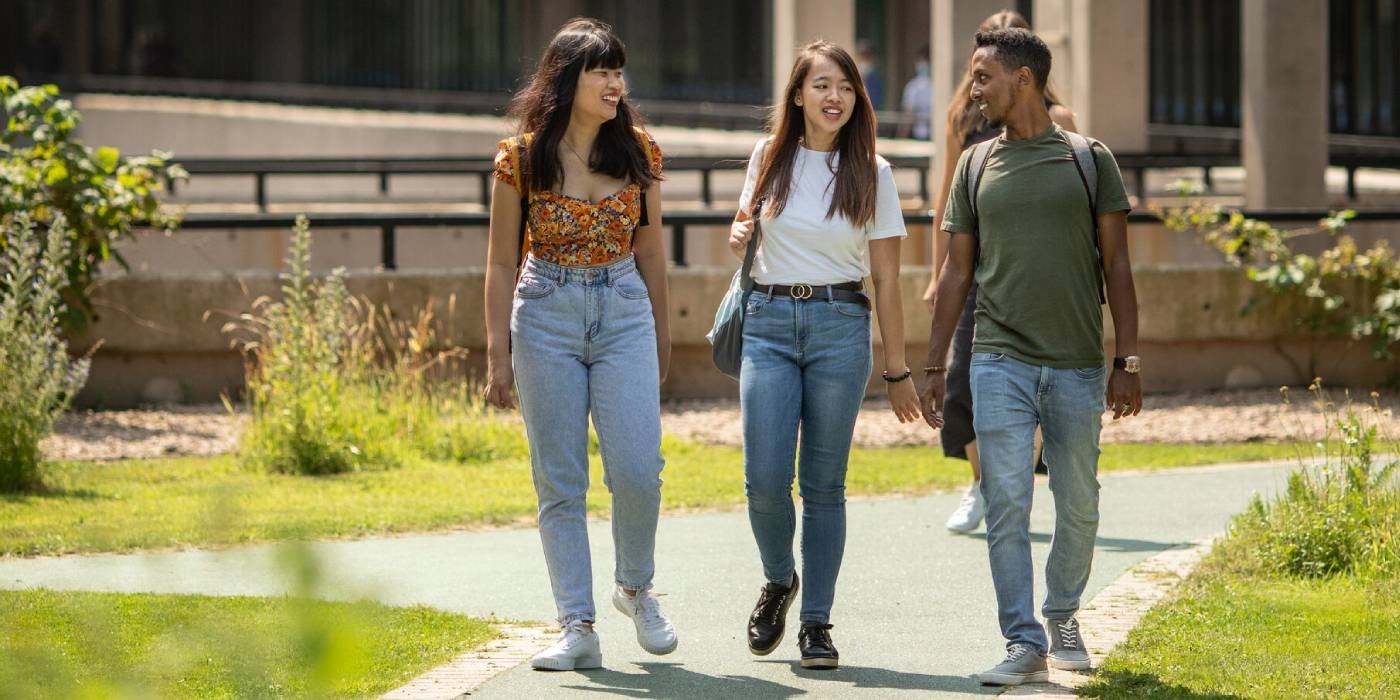 Three students walk through the Sustainable Garden on campus.
