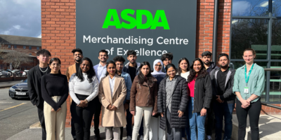 MSc Management students stand with Jess, ASDA manager, in front of ASDA MCE signage.