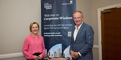 Julia Bennell and Will Stratton-Morris in front of a banner saying ' Corporate Wisdom'