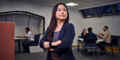 Woman standing in the middle of an office with arms folded looking confidently off camera