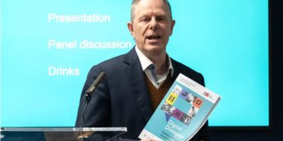 Professor Mark Stuart holding a copy of the Digit report, speaking at an event