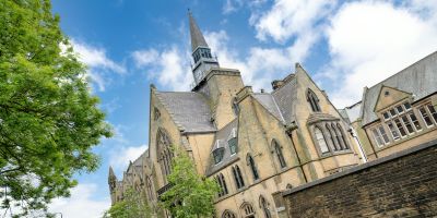 Large, historic building against a blue sky with clouds
