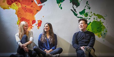 Three students sat under world map