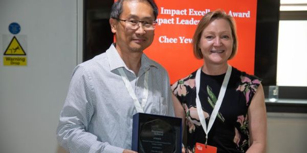 Chee Wong, holding his award, and Julia Bennell, smiling at the camera