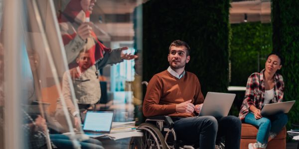 People working together in a modern office setting with laptops and collaborative seating.