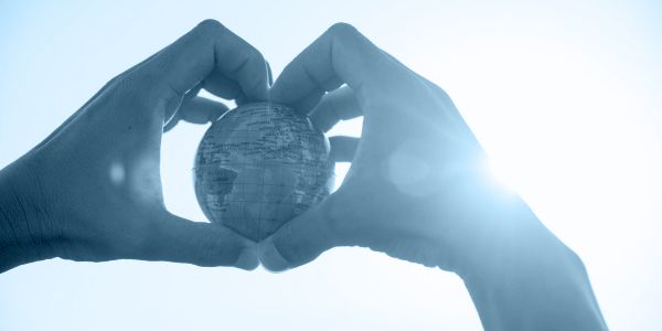 Hands holding a small globe, with a blue overlay on top