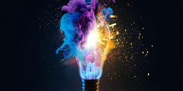 The image shows bright colours bursting forth from an exploding lightbulb against a black background.