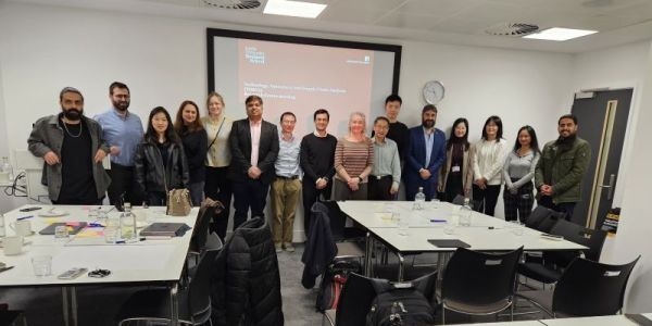 16 members of TOSCA stood up in front of a presentation screen