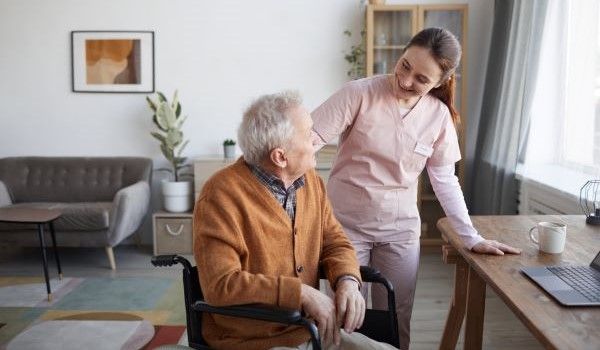 Nurse smiling at elderly man in wheelchair