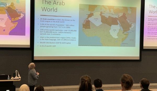 Dr Deema Refai presenting in front of a screen with a map on and the heading "The Arab World"