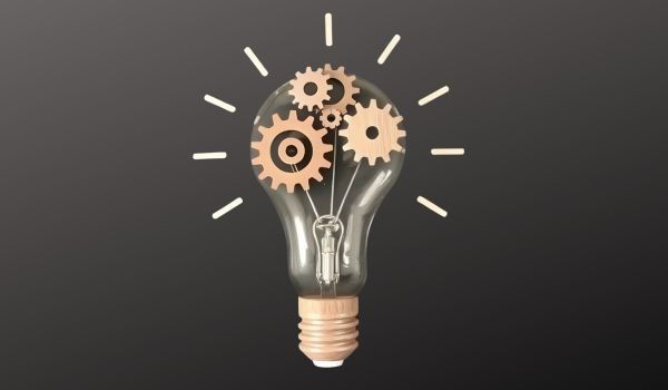 Lightbulb with cogs inside it on a black background