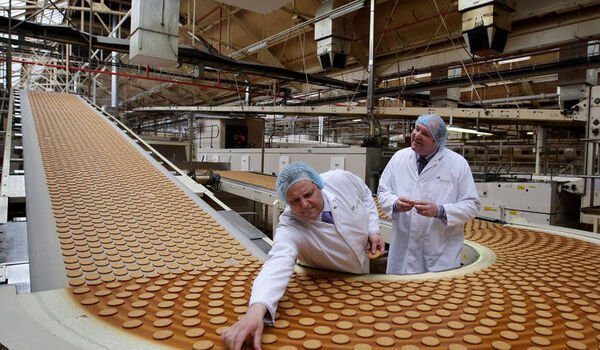 Officials standing besides a factory production line