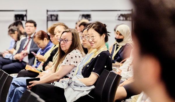 Conference attendees sat on chairs, listening to a speaker who is out of the shot