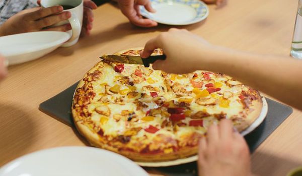 Photograph of an oven pizza being cut