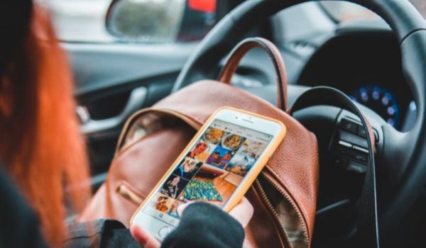 Person scrolling through photos on a phone whilst sat in a car