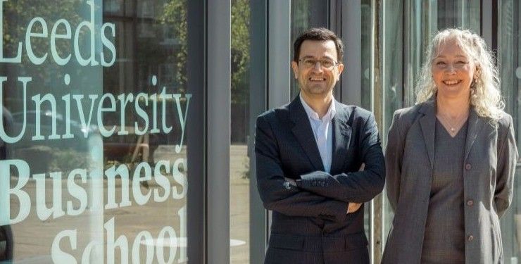 Drs Mahdi Bashiri and Nicky Shaw stood outside a building, next to a window with Leeds University Business School branding on.