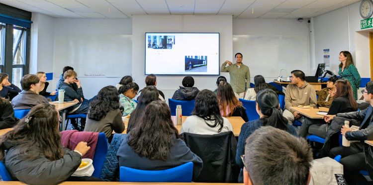 Students listening to Renato Barrientos present at the front of a classroom.