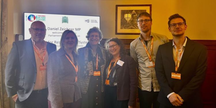 William Young, Gulbanu Kaptan, Elizabeth Morgan, Anne Tallontire, Steffen Hirth and Romain Crastes Dit Sourd stood together, smiling at the camera, in front of a screen, wearing visitor lanyards.