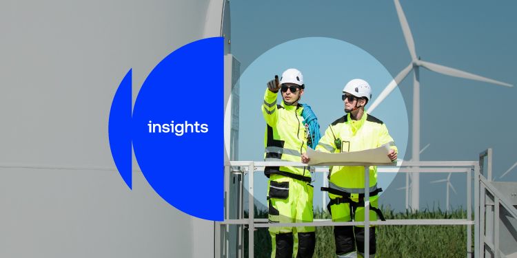 Two workers in high-visibility safety clothing on a wind turbine platform with wind turbines in the background. There is a blue ‘insights’ graphic overlay.
