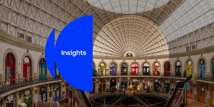Interior of a circular shopping arcade - The Corn Exchange - with colour shopfronts beneath a glass-domed roof. There is a blue "insights" graphic overlay.