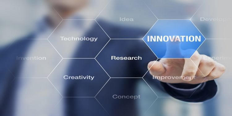 The image shows the torso of a man in business attire with his finger pressing the forefront of the image selecting the word 'Innovation' out of a hexagonal diagram of business-related terms.