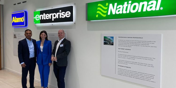 Sophie stands with two enterprise managers, in front of the enterprise signage