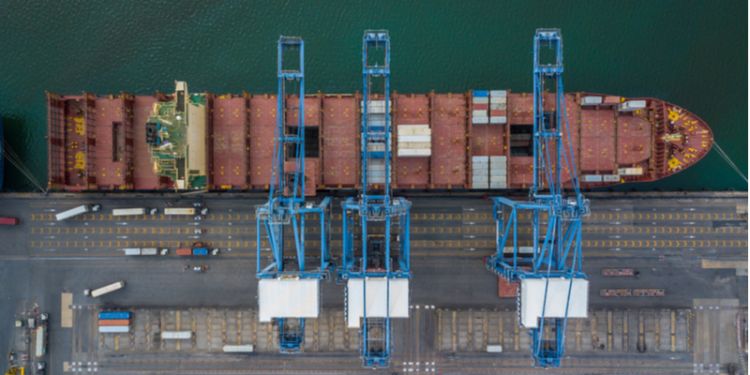 Shipping container at dock with crane loading goods