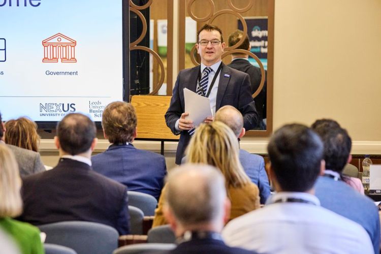 Gareth Scargill delivering a presentation in front of a seated audience at the Supply Chain Summit