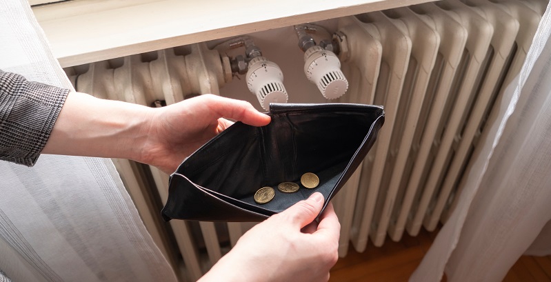 Open wallet with only a few coins in, next to a radiator