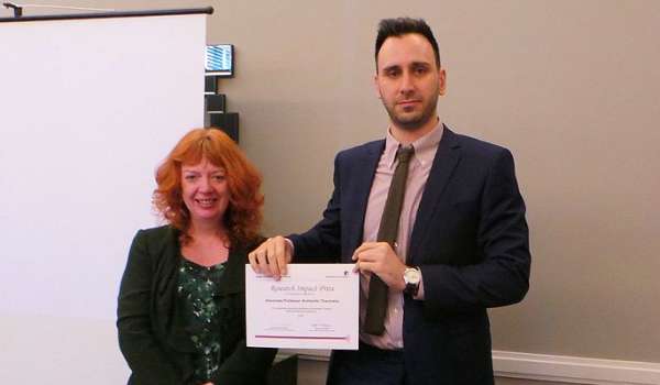 Photograph of Cathy Cassell presenting Aris Theotokis with his award.
