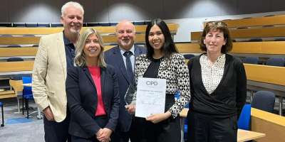 Student Allesandra Macasa holding her award surrounded by staff from the Business School and the CIPD.