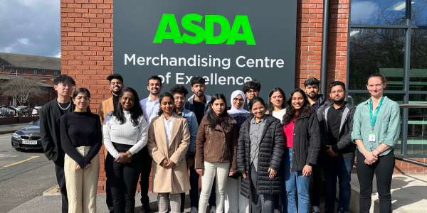 MSc Management students stand with Jess, ASDA manager, in front of ASDA MCE signage.