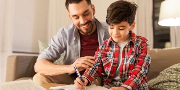 A father is shown helping his son with homework.