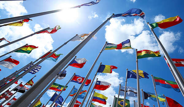 Upwards shot of flags of the world in front of blue sky