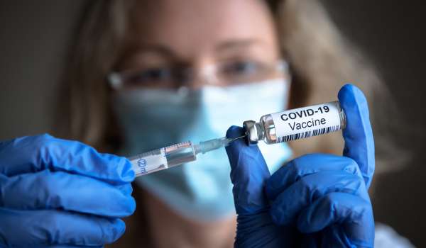 A scientist holds a syringe and a bottle with coronavirus vaccine